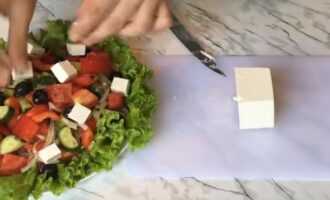 Нарезаем сыр Фета крупными кубиками и выкладываем на салат.